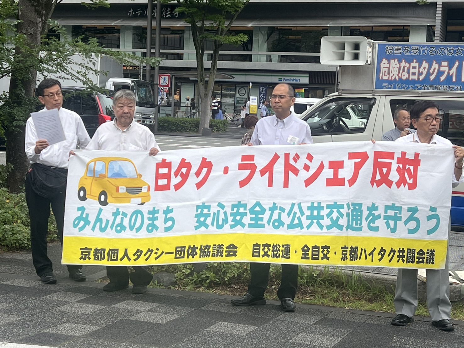横断幕を拡げて通行人へアピールした=6月23日、京都・京都市役所前